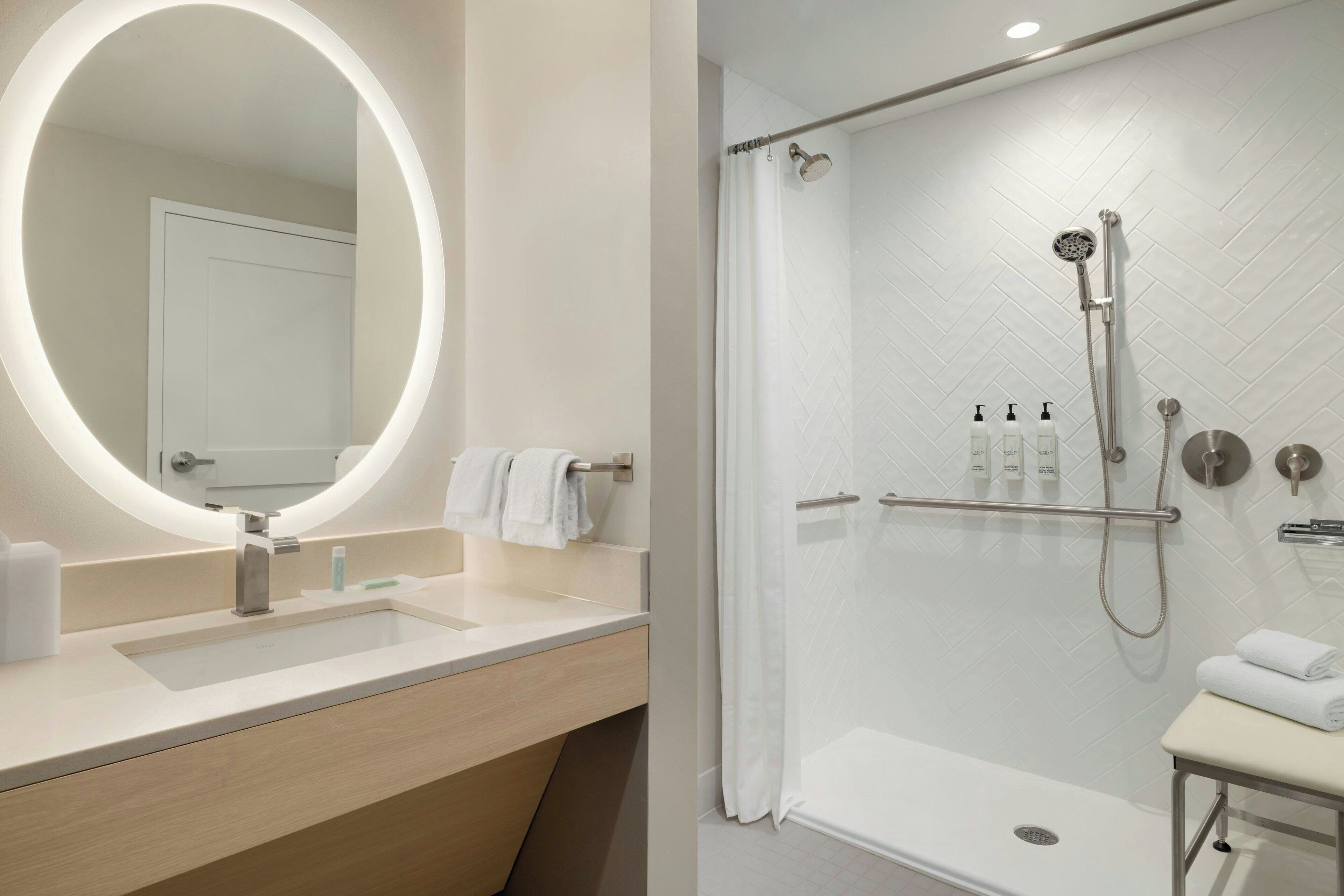 A modern bathroom with a large mirror, a sink, and a shower area.