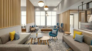 A modern hotel lobby with a seating area, large windows, and a reception desk. - TownePlace Suites by Marriott Williston (Williston)