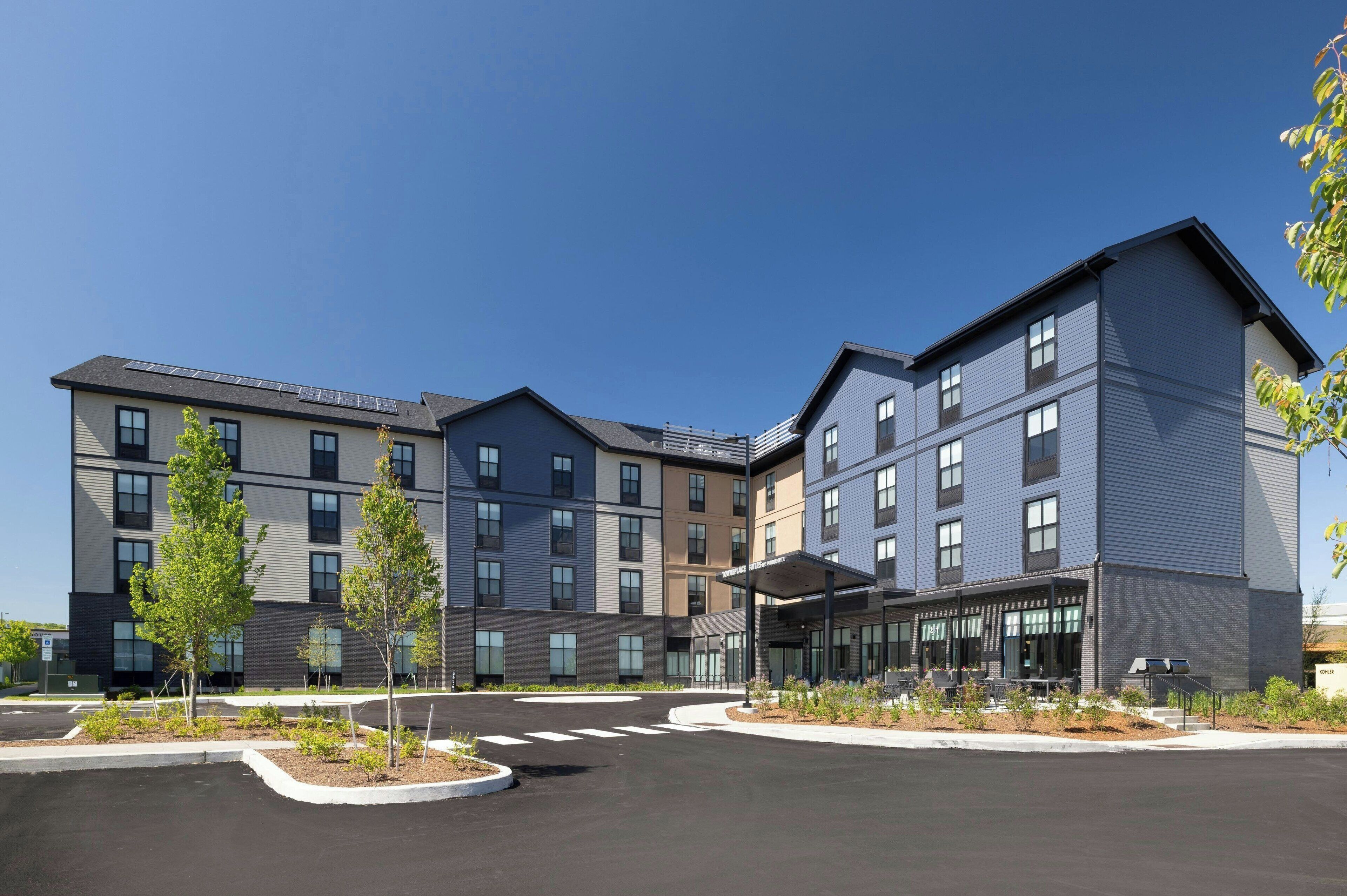 Un hôtel à plusieurs étages, doté d’un design moderne, comprenant une entrée couverte et un parking.
