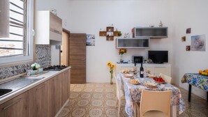 A compact kitchen with a window, a dining area with a table set for two, and a TV mounted on the wall.