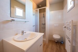 Een douche, handdoeken, zeep, toiletpapier