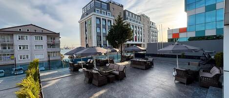 A rooftop terrace with outdoor seating and a view of the cityscape.
