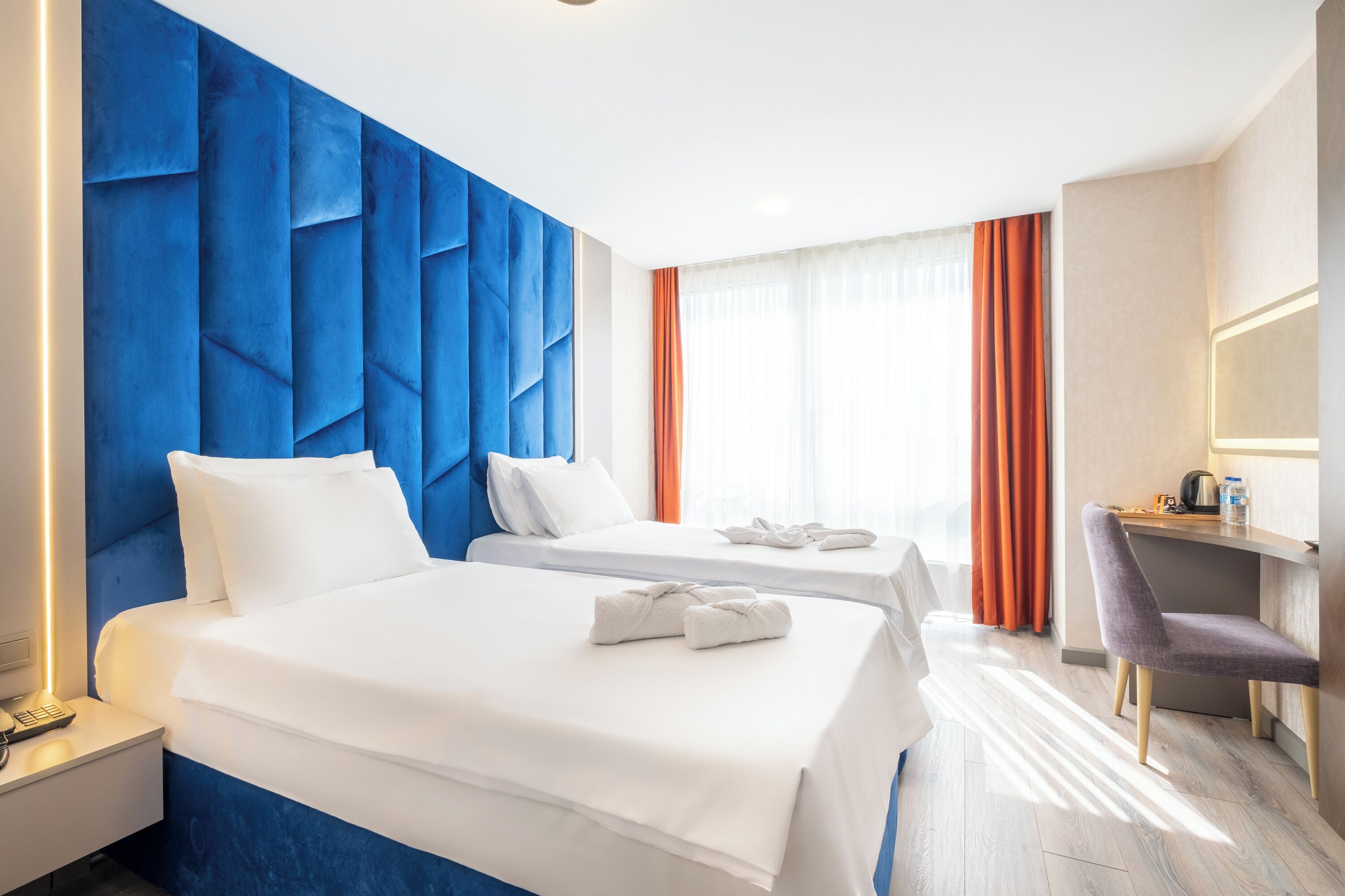 A hotel room with two beds, a desk, and a chair.