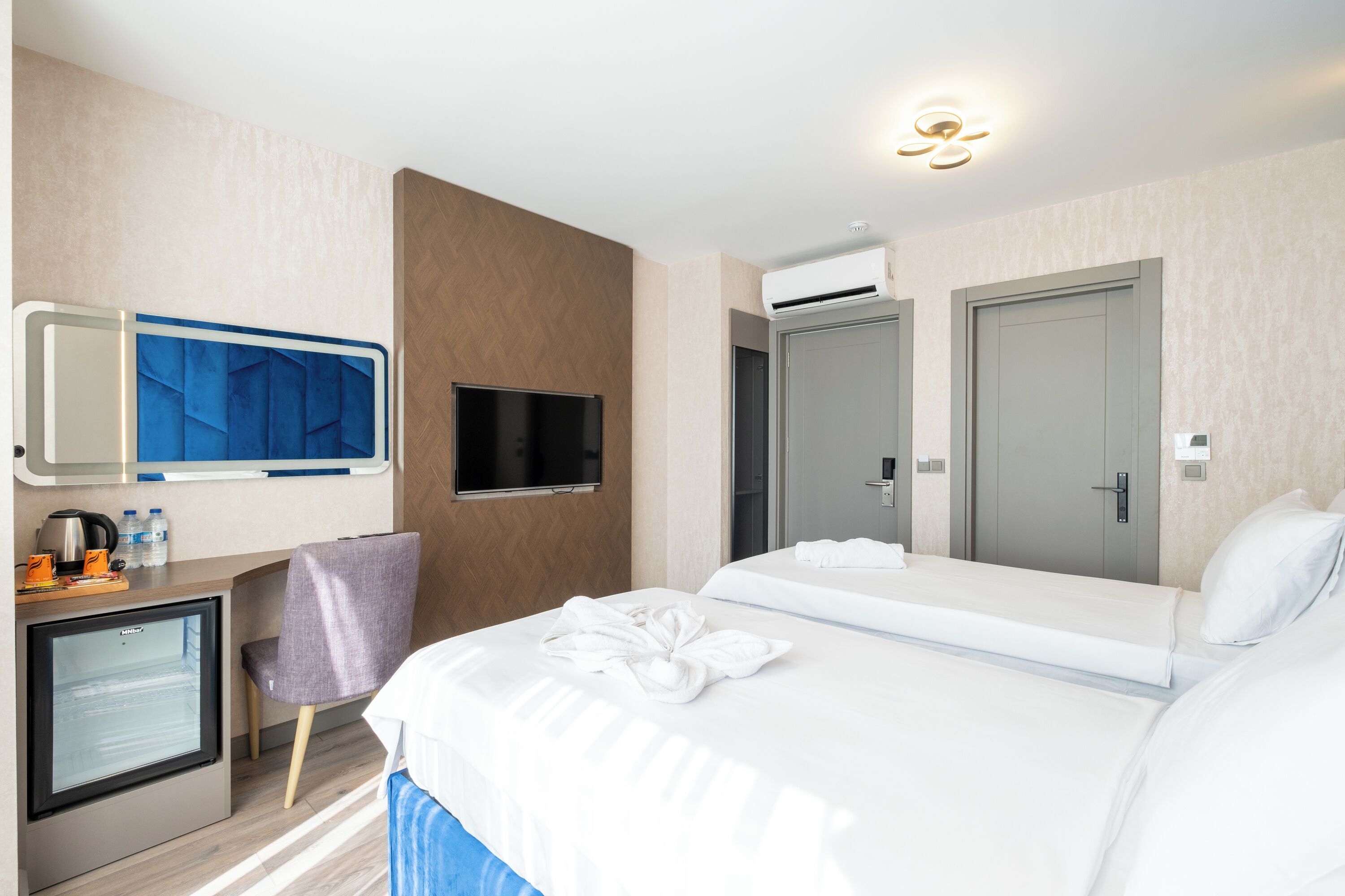 Habitación de hotel con cama, televisión, minibar y zona de ducha.
