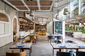 En modern restaurang med bord i marmor, hängande lampor och en central bardisk.