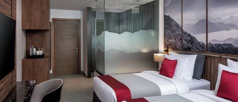 Habitación de hotel con dos camas, un escritorio, una silla, un televisor y un mural con vistas a la montaña.