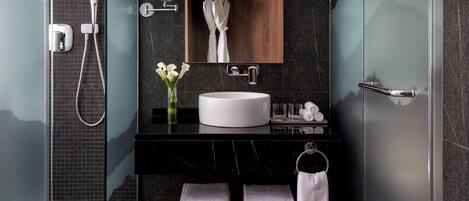 A modern bathroom with a glass shower enclosure, a wooden vanity with a white sink, and a mirror above the sink.
