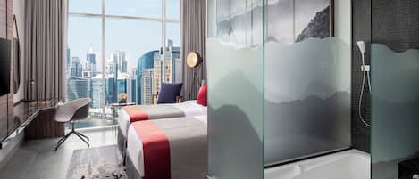 Habitación de hotel con vistas a la ciudad, una cama grande, un escritorio, una silla y una bañera.