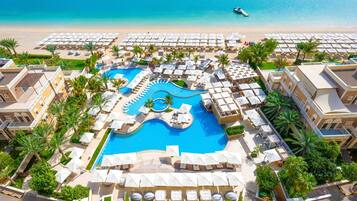 A resort with a central swimming pool, sun loungers, and umbrellas.