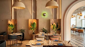 A restaurant with round tables, chairs, and hanging pendant lights.