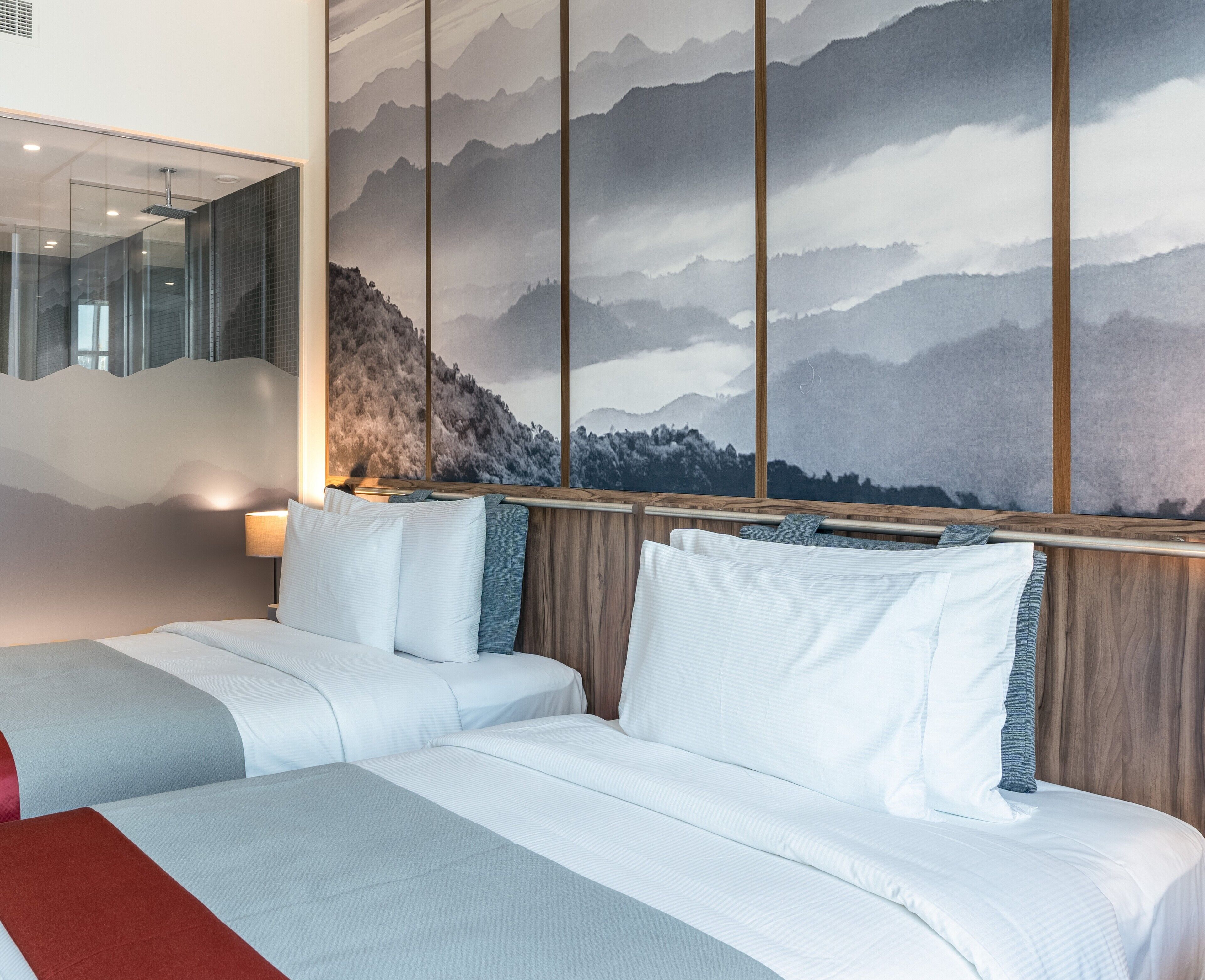 A hotel room with a large bed, a wooden headboard, and a mountain view mural.