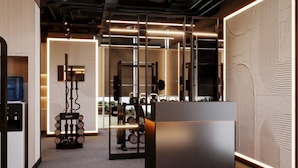 A modern gym with exercise equipment, a reception desk, and a large mirror. - Grand Millennium Business Bay (Dubai)