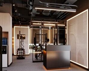 Un gimnasio moderno con equipamiento de ejercicio, una recepción y un espejo grande.