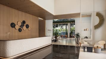 A modern lobby with a reception desk, seating area, and a large window providing natural light.