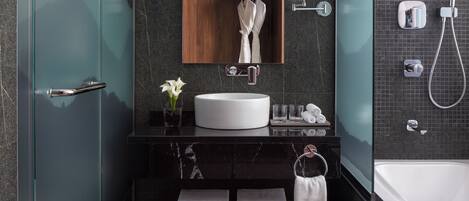 Un baño moderno con un lavabo grande de color blanco, un armario de medicinas de madera, un box de ducha de vidrio y una bañera.