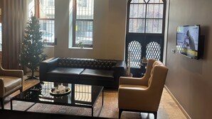 Un salon moderne avec un canapé en cuir, une table basse en verre et un téléviseur fixé au mur.