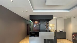 Un hall d’accueil moderne avec un sol en marbre, un comptoir d’accueil et une horloge murale.