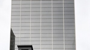 Un bâtiment sur lequel on peut lire l’inscription « THE WAY HOTEL », avec une structure moderne en verre à l’arrière.