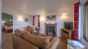 A cozy living room with a fireplace, a television, and a sofa. - Ash Tree Lodge - sleeps 4 guests in 2 bedrooms (Appin)
