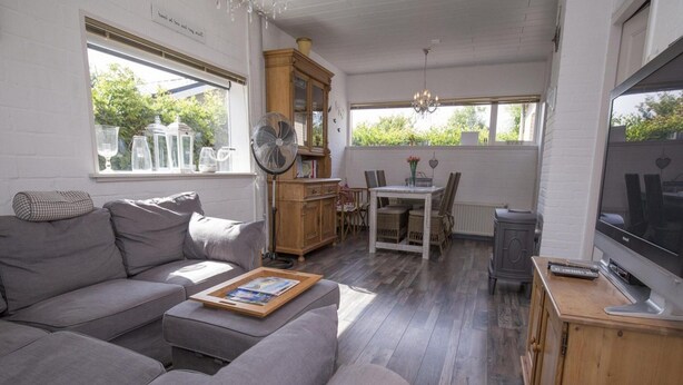 Een gezellige woonkamer met een grijze bank, een houten kast en een televisie.