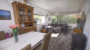 Een gezellige woonkamer met een bank, een eettafel met stoelen, een televisie en een houtkachel.