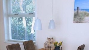 Un'area pranzo con un tavolo e sedie in legno, una finestra con persiane e una lampada a sospensione.