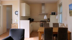 Una cucina compatta con zona pranzo, completa di mobili, un forno a microonde e un tavolo con sedie.