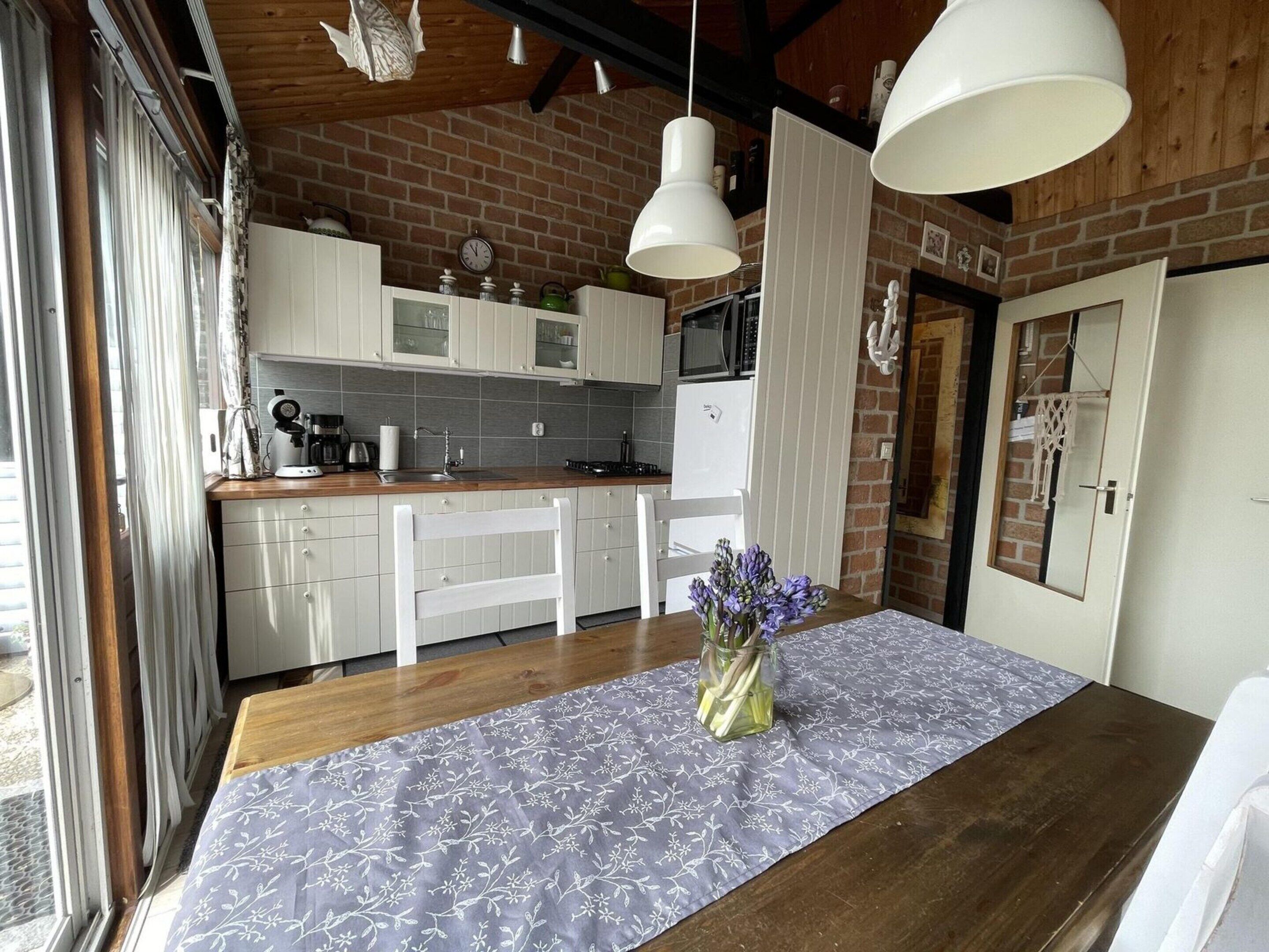 Una cocina con armarios blancos, encimera de madera y comedor con mesa y sillas.