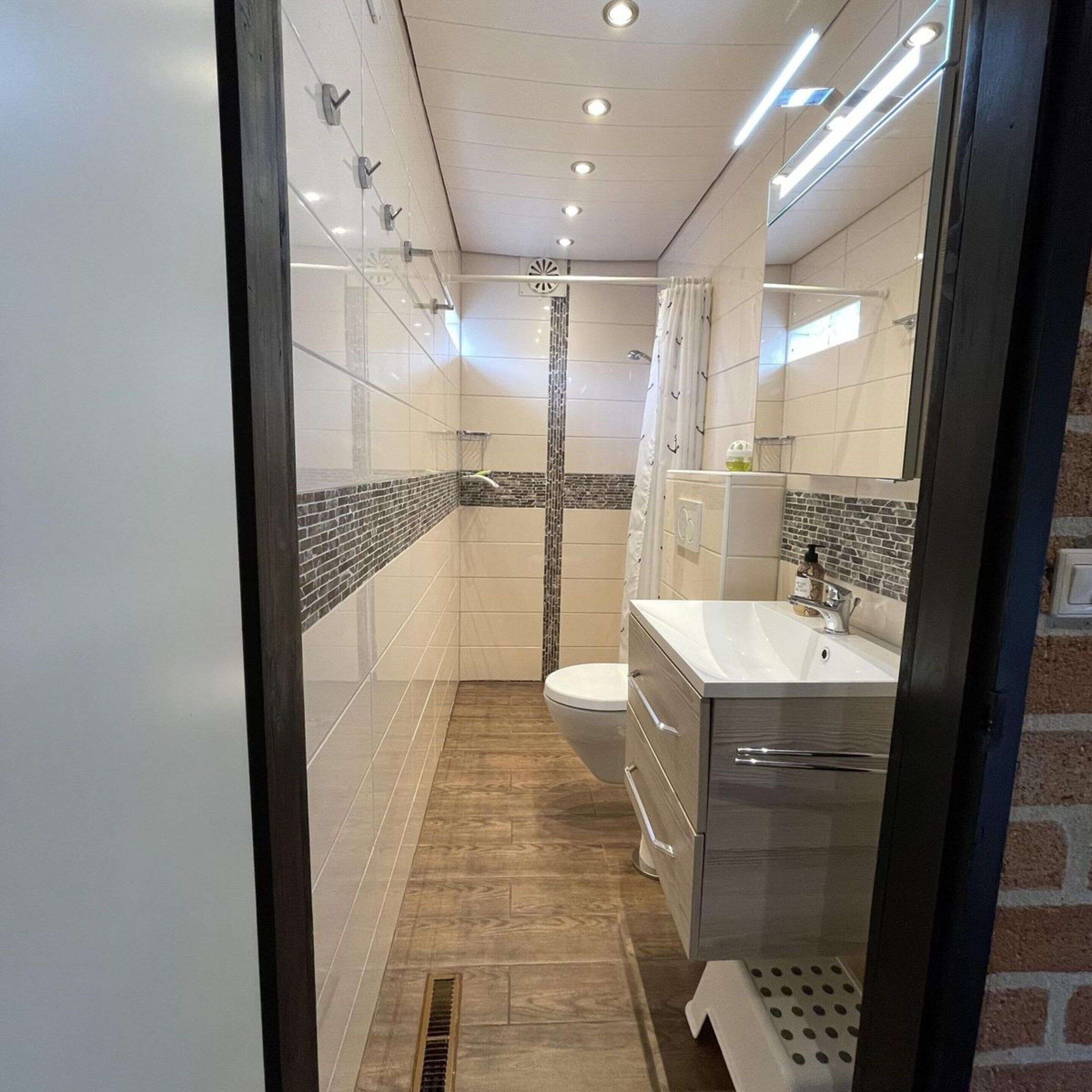 A modern bathroom with a shower, toilet, and vanity.