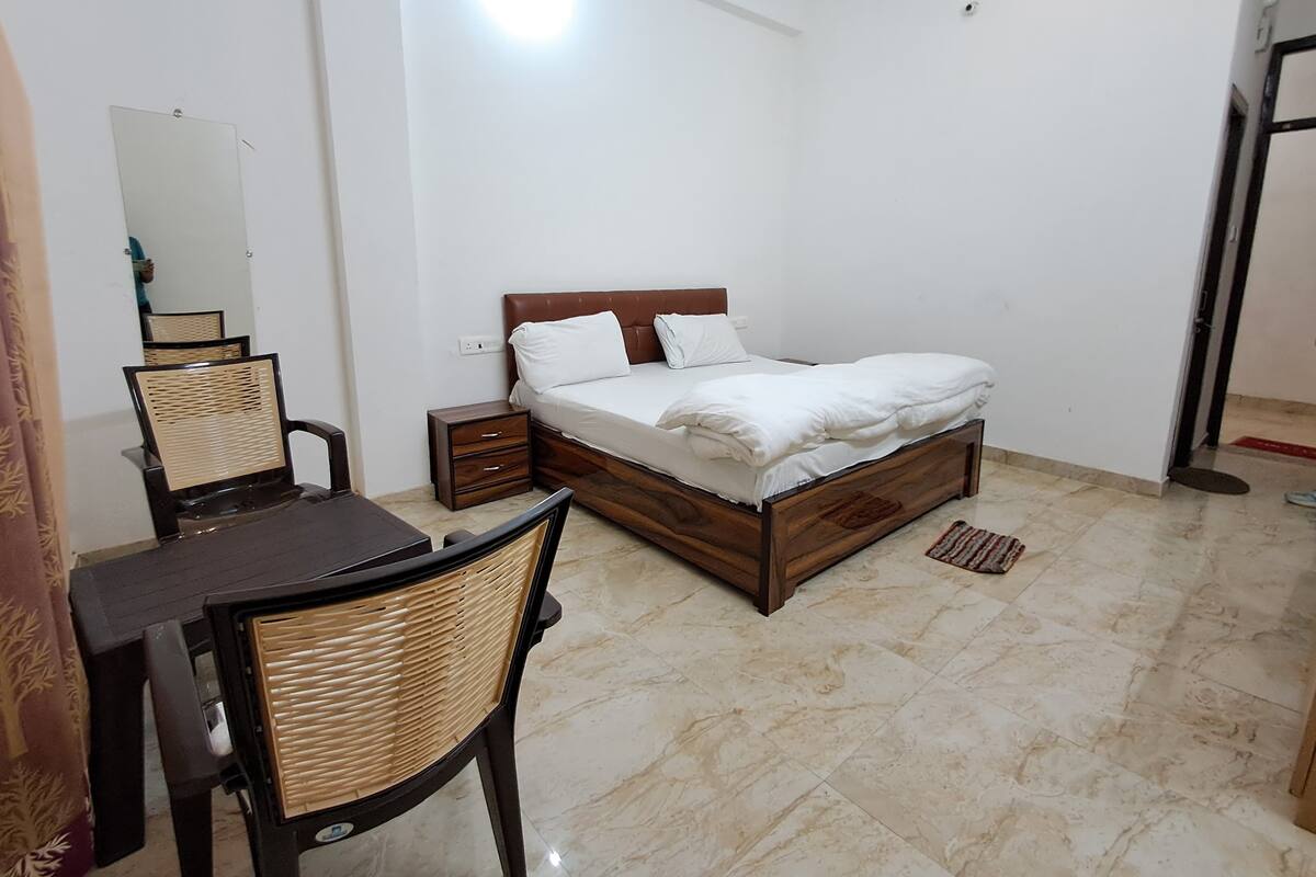 A bedroom with a wooden bed, a desk, and a chair.
