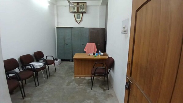 Una pequeña oficina con un escritorio, sillas y una puerta de madera.