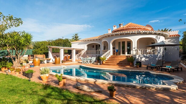 Ein Haus mit Schwimmbad, Gartenmöbeln und einer Terrasse.