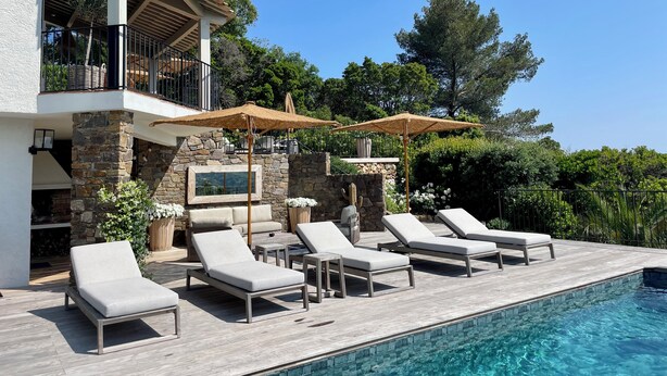 A poolside area with lounge chairs and umbrellas, a stone wall, and a clear blue sky. - Pura Vida, 5-bedroom villa with sea view  (La Croix-Valmer)