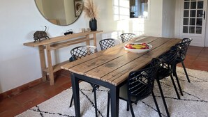 A dining area with a wooden table, black chairs, a mirror, and a vase with pampas grass. - Pura Vida, 5-bedroom villa with sea view  (La Croix-Valmer)