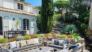A patio with outdoor furniture, a stone wall, and a variety of plants. - Pura Vida, 5-bedroom villa with sea view  (La Croix-Valmer)