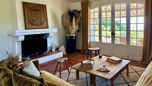 A living room with a fireplace, a sofa, a coffee table, and a view through a large window. - Pura Vida, 5-bedroom villa with sea view  (La Croix-Valmer)
