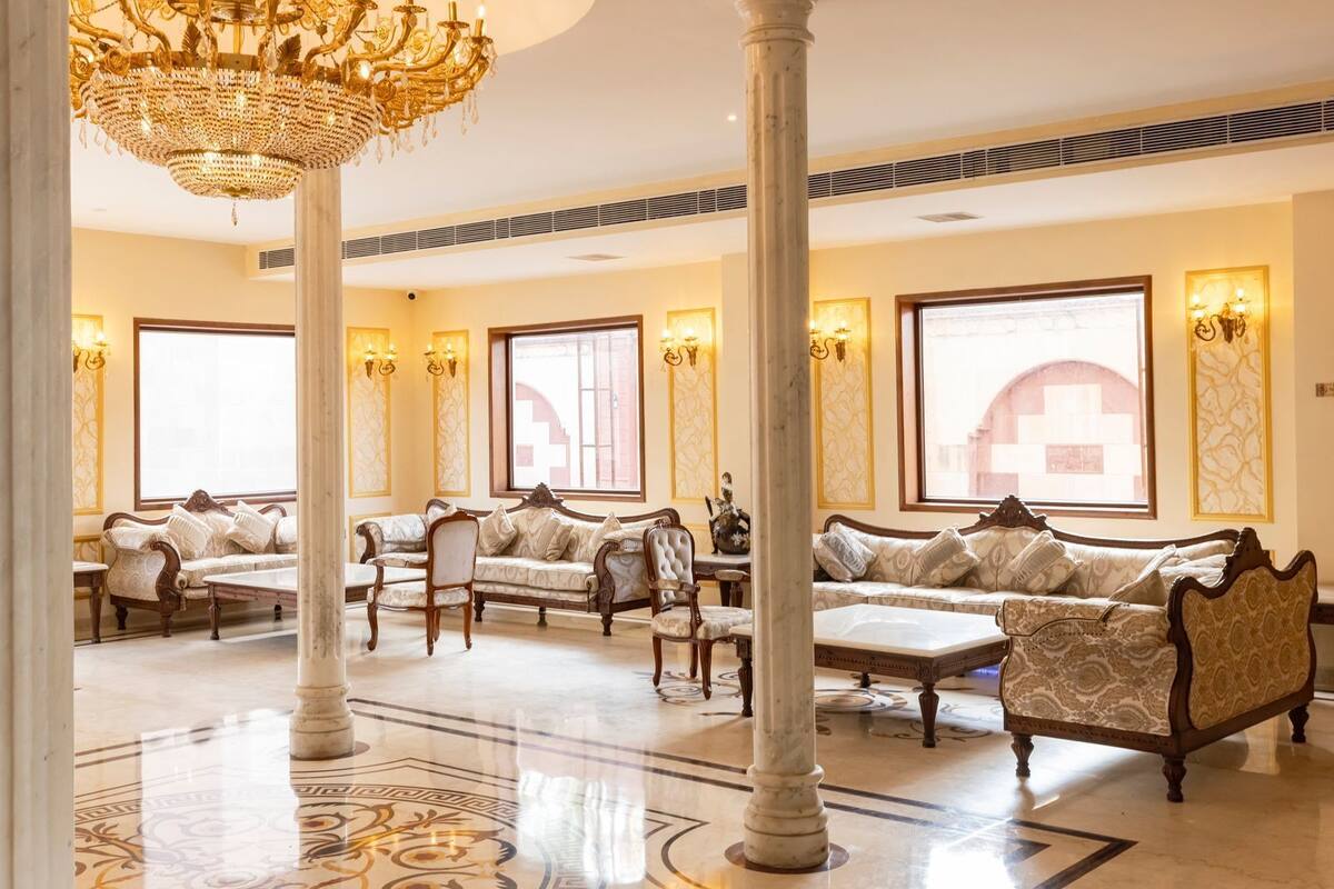 A luxurious lobby with ornate chandeliers, elegant sofas, and a grand staircase.
