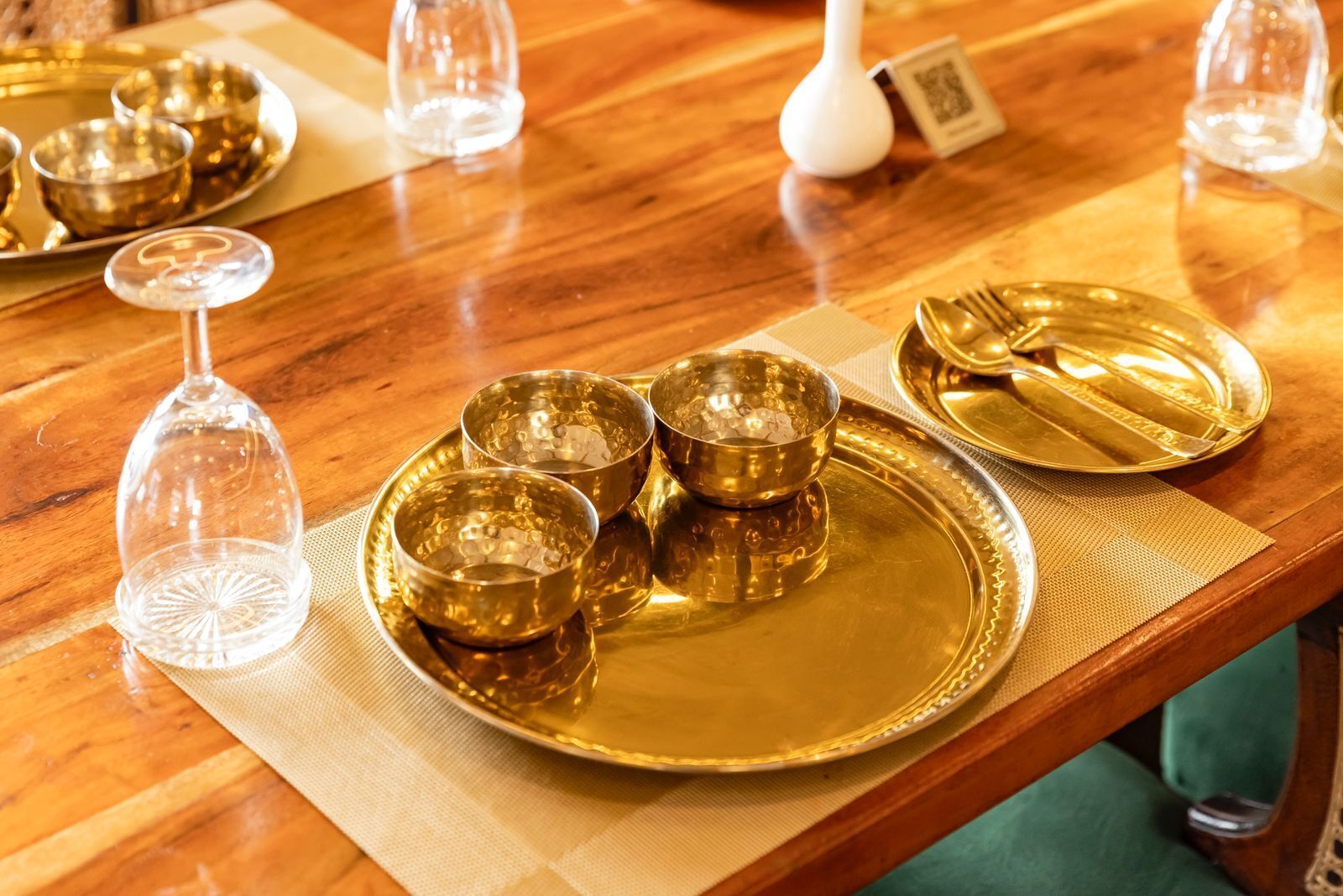 A table set with golden dinnerware, including plates, bowls, and a wine glass.