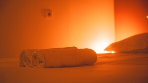 A room with a bed, a rolled-up towel, and a wall-mounted light fixture. - Le Cube Soma - Large T3 (Tours)