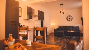 A cozy living room with a sofa and a dining area with a table set for breakfast. - Le Cube Soma - Large T3 (Tours)