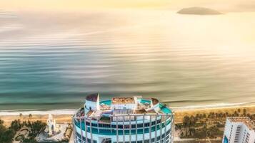 A high-rise hotel with a rooftop pool and a view of the beach.