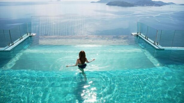 Eine Frau in einem Pool mit Blick auf den Ozean und entfernte Inseln.