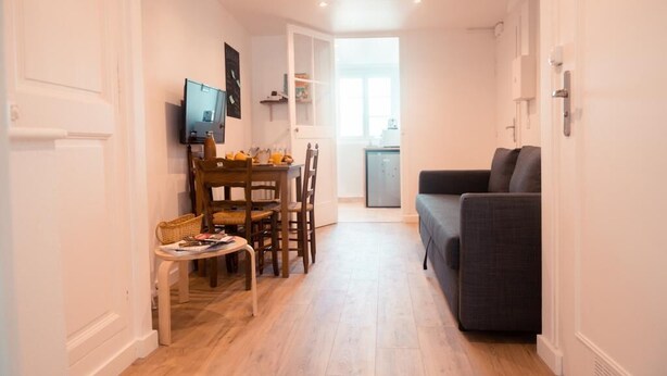 A compact living space with a dining area, a sofa, and a TV mounted on the wall.