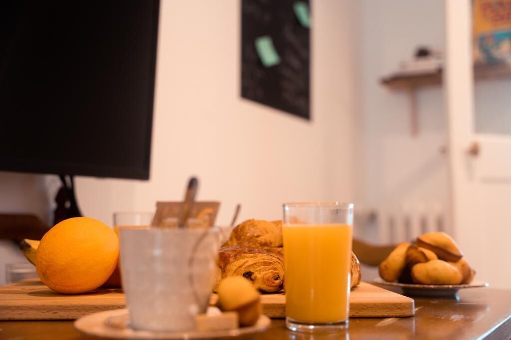 Desayuno con un croissant, naranja y jugo de naranja sobre una mesa de madera.