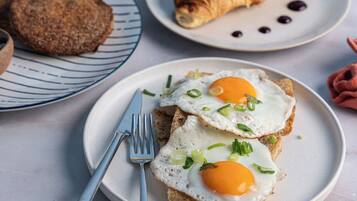 A breakfast setting with croissants, eggs, and a glass of orange juice on a table.