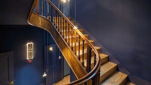 Un escalier en colimaçon avec des rampes et un plancher en bois, éclairé par des lampes suspendues.