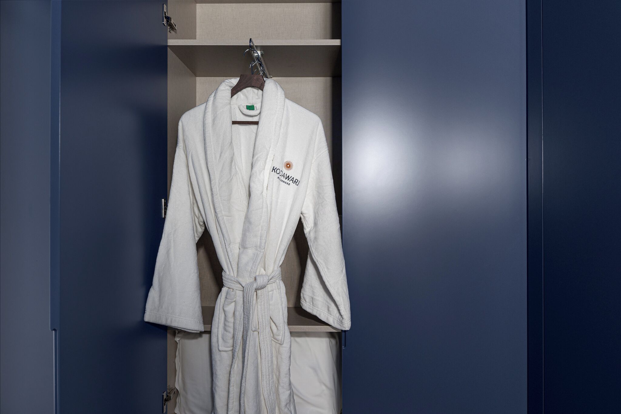 Une robe blanche est suspendue dans un placard à un cintre en bois.