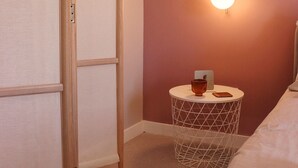 A bedroom with a bed, a bedside table with a lamp, and a wall-mounted light. - Charming studio with AC and WiFi in enchanting Rabat - Studio No. 3  (Rabat)