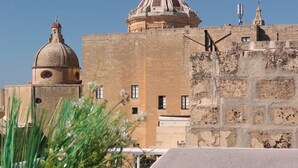 A building with a dome and a smaller tower, a stone wall, and a wooden bench with plants. - Charming studio with AC and WiFi in enchanting Rabat - Studio No. 3  (Rabat)
