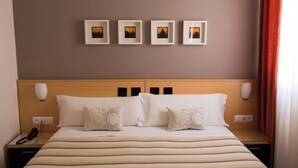 A hotel room with a bed, bedside tables, a phone, and framed pictures on the wall. - Hostal Albero by eme hoteles (Sanlucar la Mayor)